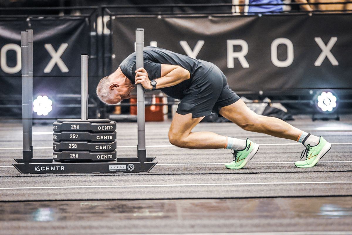 An everyday athlete pushing a sled at a HYROX event