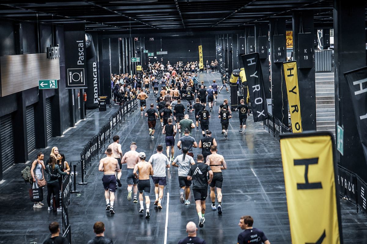Hundreds of athletes running the course at an indoor HYROX race